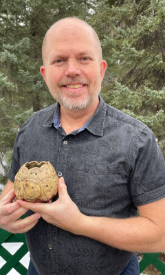 A mid-fifties man holding a piece of pottery.