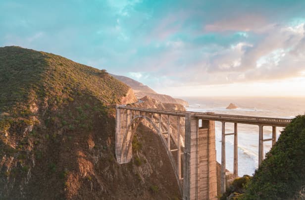 A scenic view of a bridge with a coast in the background.