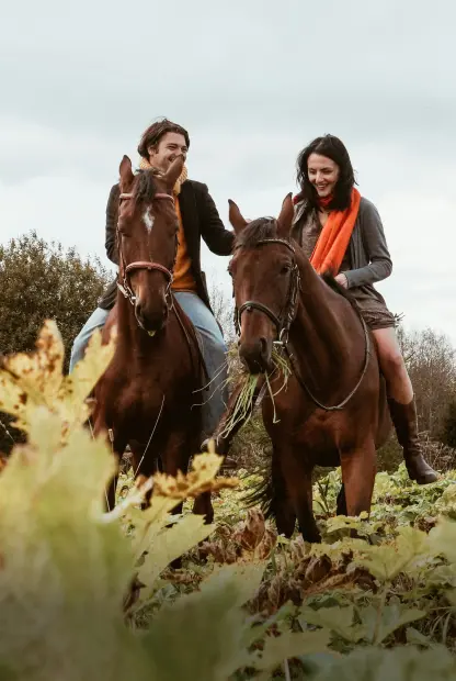 Two people smiling while riding on horseback