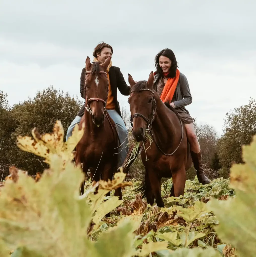 two people smiling while riding on horseback